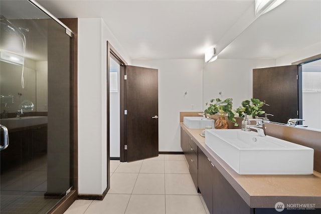 full bath featuring a sink, baseboards, tile patterned flooring, and a shower stall