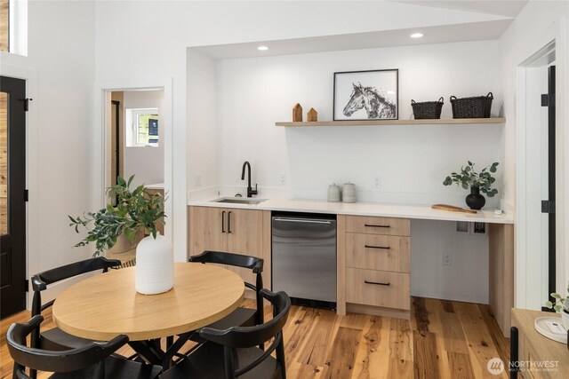 bar with stainless steel dishwasher, a sink, indoor wet bar, recessed lighting, and light wood-style flooring