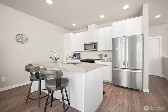 4818 Springside St, Bellingham, WA 98226 - kitchen with stainless steel appliances, wood finished floors, a kitchen bar, an island with sink, and white cabinetry