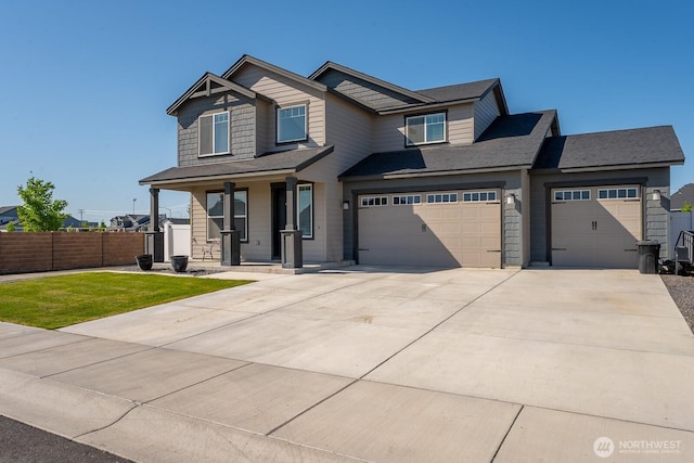 craftsman house with fence, a front lawn, a garage, concrete driveway, and covered porch