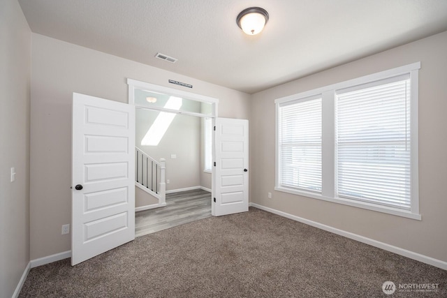 carpeted spare room with baseboards and visible vents