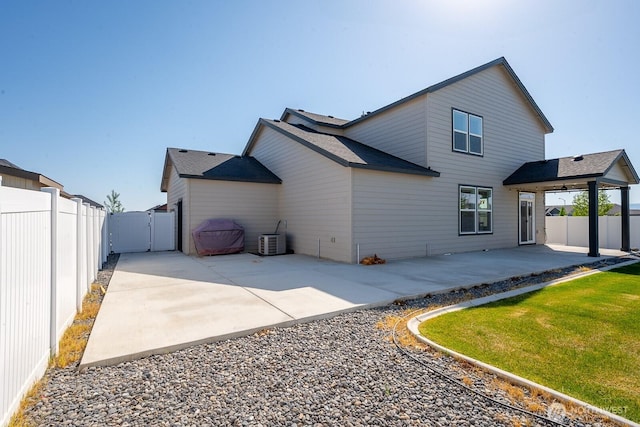 rear view of house with roof with shingles, central AC, a fenced backyard, a gate, and a patio
