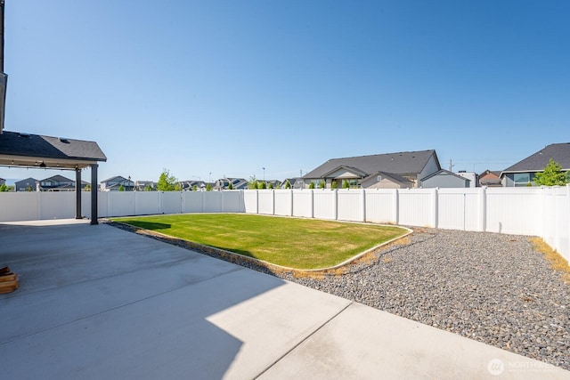 view of yard featuring a residential view, a fenced backyard, and a patio area