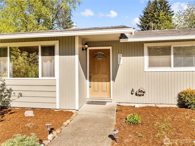 entrance to property featuring roof with shingles