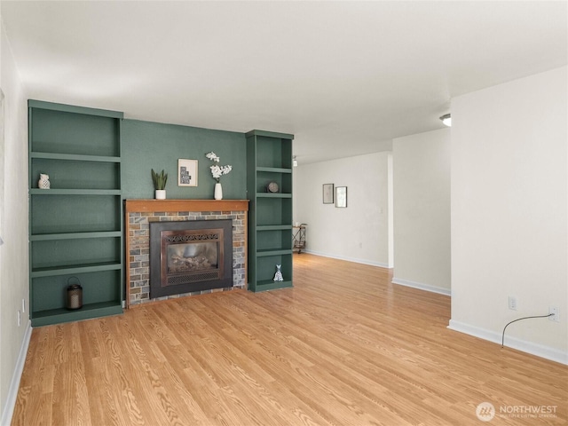 living room with a brick fireplace, baseboards, and wood finished floors