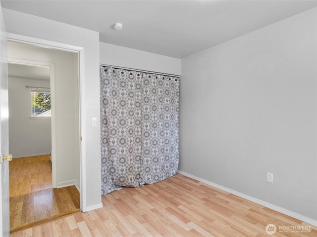 spare room with baseboards and wood finished floors