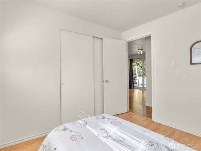 bedroom featuring a closet, light wood finished floors, and baseboards