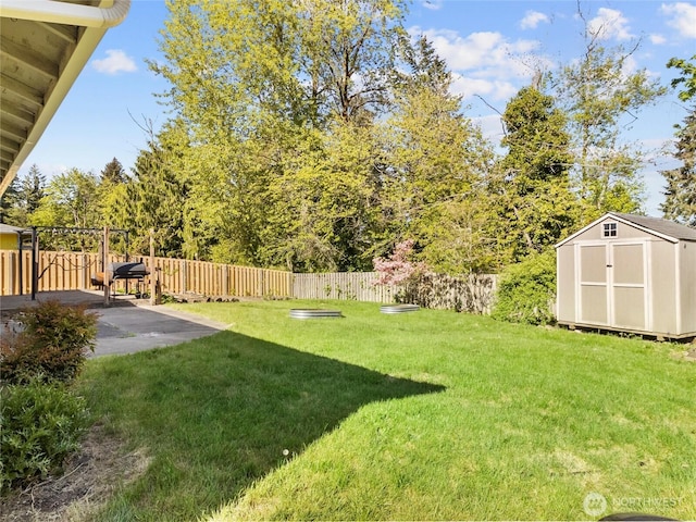 view of yard with an outdoor structure, a fenced backyard, a patio area, and a storage shed