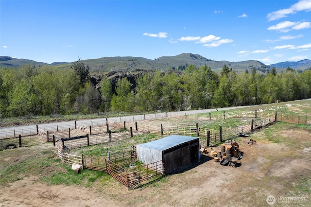 view of yard with a view of trees, an outbuilding, a mountain view, a rural view, and an exterior structure