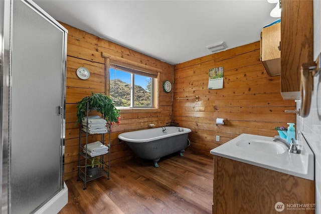 bathroom with visible vents, a freestanding tub, wood finished floors, wooden walls, and a shower stall