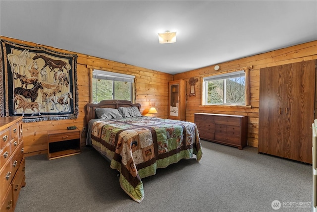 bedroom with wooden walls, multiple windows, and carpet