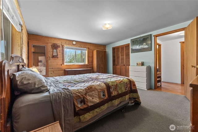 carpeted bedroom with wooden walls and a closet