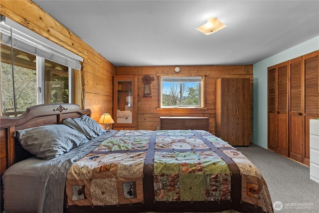 carpeted bedroom featuring wooden walls