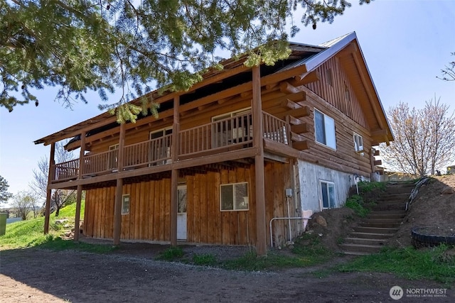rear view of property featuring stairway, board and batten siding, and log siding