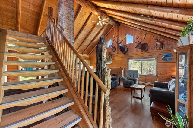 staircase featuring wood walls, wood finished floors, beamed ceiling, ceiling fan, and wood ceiling