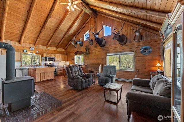living room with a wood stove, wooden walls, baseboard heating, high vaulted ceiling, and wooden ceiling