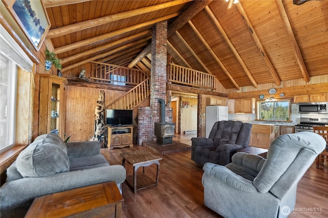 living room featuring beam ceiling, wood ceiling, a wood stove, and high vaulted ceiling