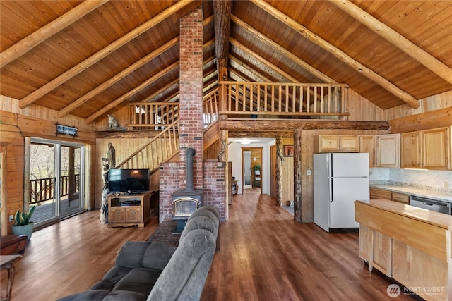 living room with wooden walls, high vaulted ceiling, and a wood stove
