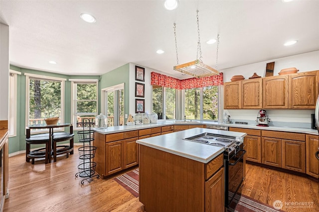 kitchen with light countertops, black electric range oven, light wood-style flooring, and a center island