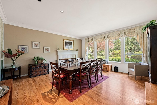dining area with crown molding, baseboards, and light wood-style flooring
