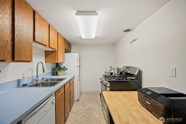 kitchen featuring stone finish floor, brown cabinets, a sink, white appliances, and butcher block countertops