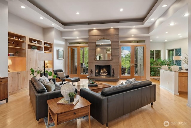 living room with a healthy amount of sunlight, recessed lighting, a tray ceiling, and light wood-type flooring