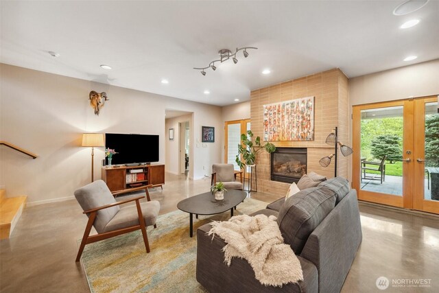 living area featuring recessed lighting, baseboards, a glass covered fireplace, and concrete floors
