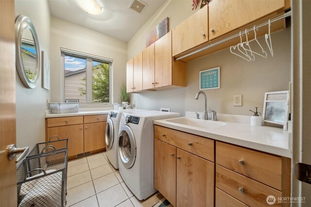 washroom featuring cabinet space, washer and dryer, a sink, light tile patterned floors, and visible vents