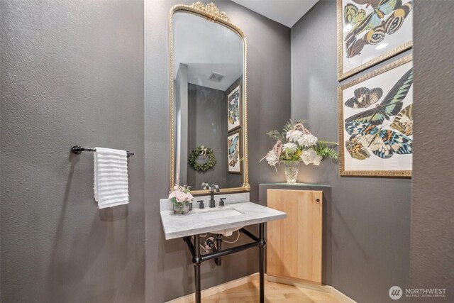bathroom with a sink, a textured wall, and visible vents