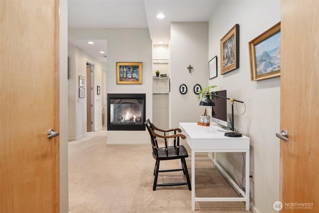 office space featuring carpet floors, recessed lighting, baseboards, and a glass covered fireplace