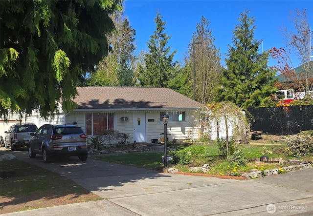 single story home with a front lawn, fence, and concrete driveway