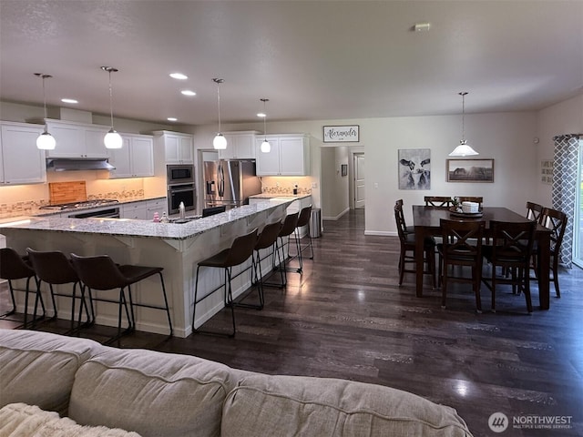 118 Woodview Ln, Napavine, WA 98596 - kitchen with a kitchen breakfast bar, dark wood finished floors, under cabinet range hood, stainless steel appliances, and recessed lighting