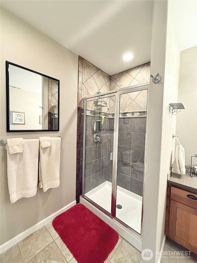 bathroom with baseboards, tile patterned flooring, a stall shower, and vanity