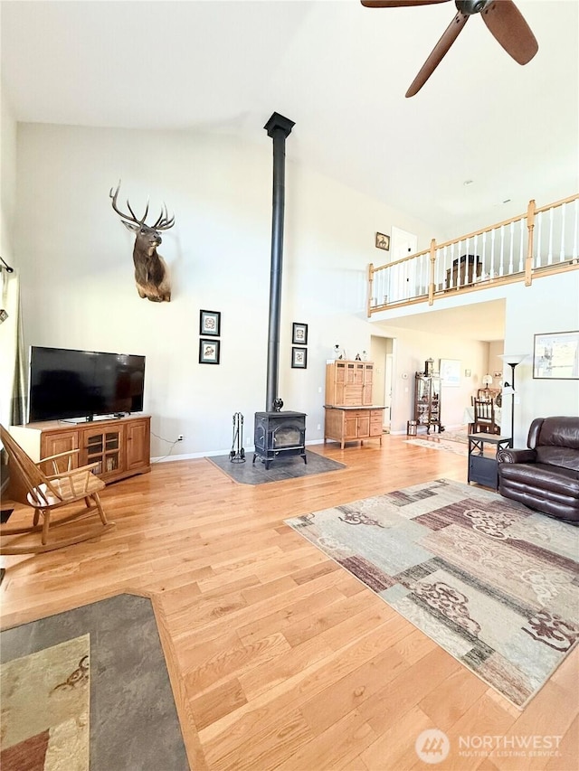 living room with ceiling fan, wood finished floors, and a wood stove