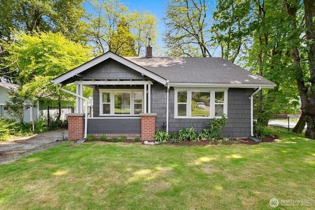 bungalow-style house featuring a chimney, a front yard, and a shingled roof