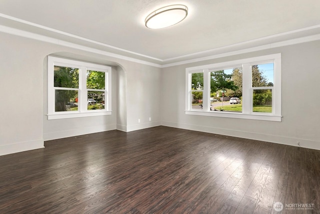 unfurnished room featuring wood finished floors, arched walkways, baseboards, and ornamental molding