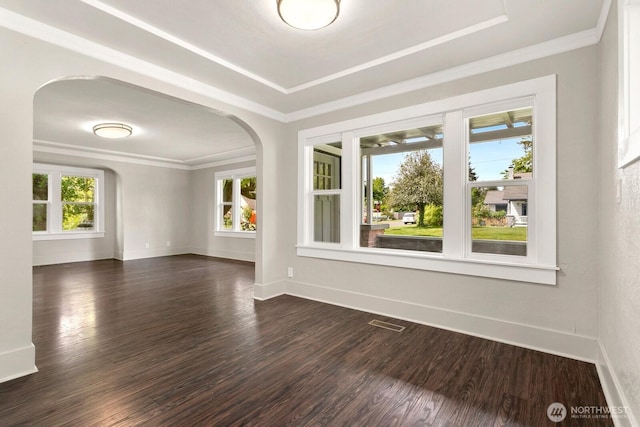 spare room with arched walkways, dark wood-type flooring, baseboards, ornamental molding, and a raised ceiling