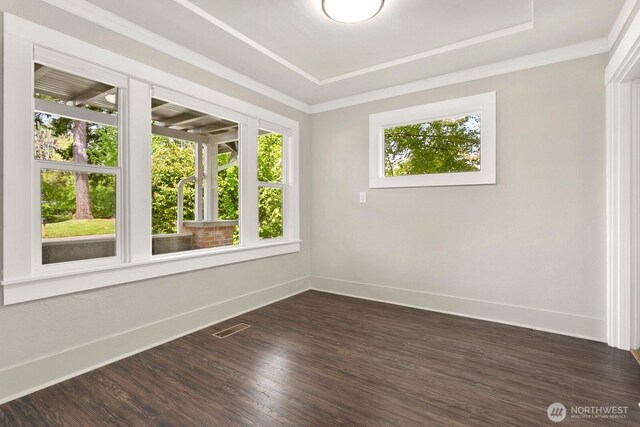 unfurnished room featuring baseboards, a tray ceiling, dark wood-style floors, and ornamental molding