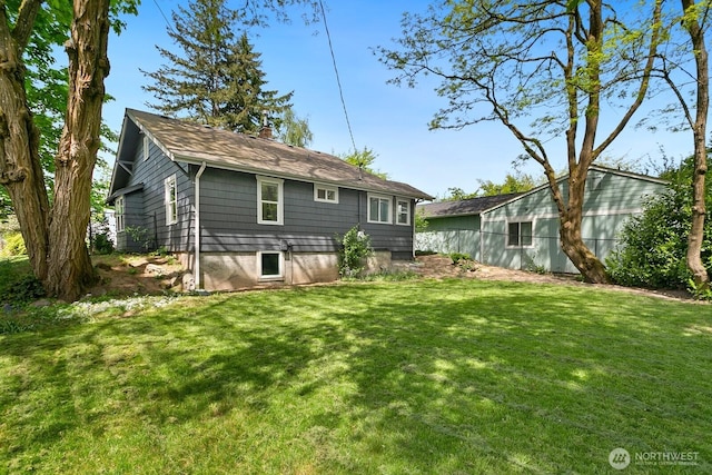 back of property featuring a lawn, a chimney, and a shingled roof