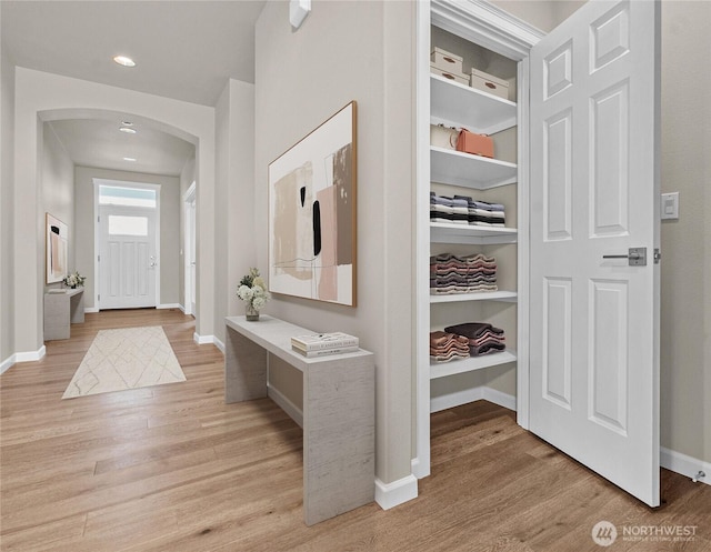 mudroom with light wood-style floors, arched walkways, baseboards, and recessed lighting