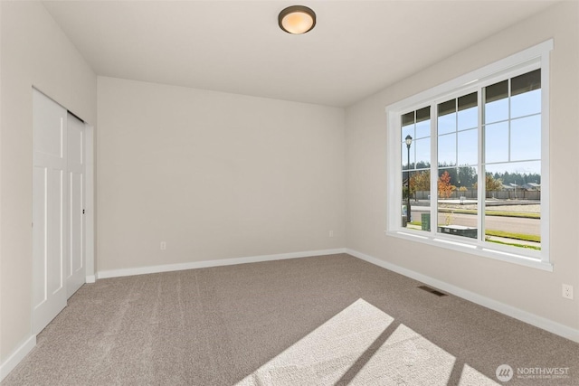 spare room featuring carpet flooring, baseboards, and visible vents