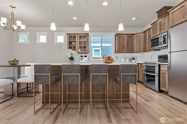 kitchen with a breakfast bar, light wood-style floors, a center island, light countertops, and stainless steel appliances