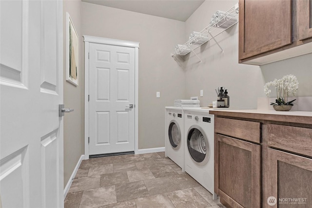 laundry room featuring baseboards, cabinet space, independent washer and dryer, and stone finish floor