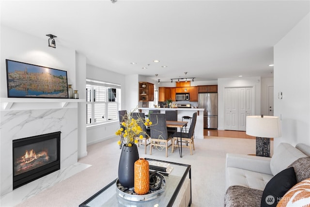 living room featuring a high end fireplace, baseboards, recessed lighting, and light colored carpet