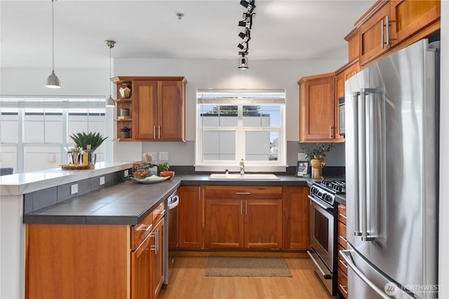 kitchen featuring a sink, dark countertops, stainless steel appliances, and brown cabinets