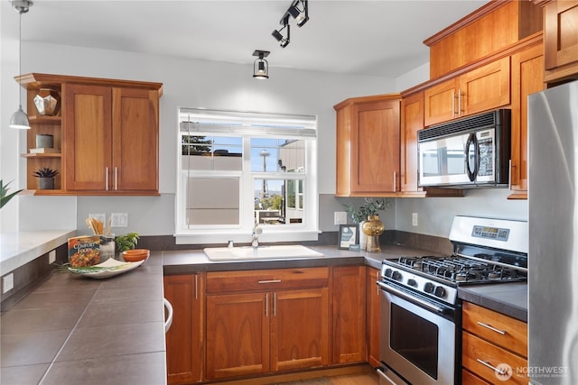 kitchen featuring brown cabinets, dark countertops, appliances with stainless steel finishes, and a sink