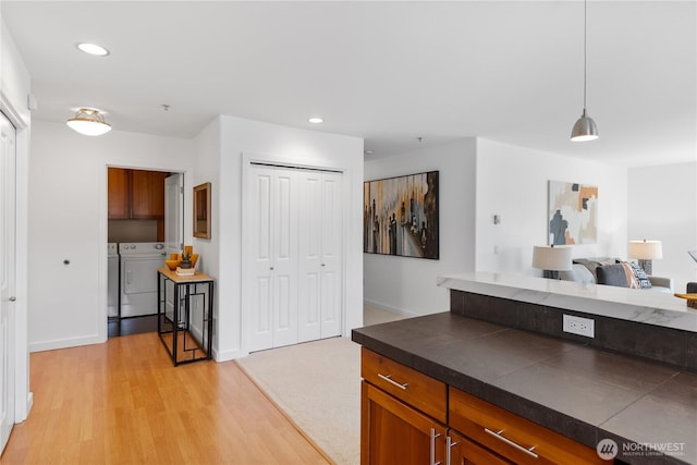 kitchen featuring dark countertops, light wood finished floors, separate washer and dryer, brown cabinetry, and recessed lighting