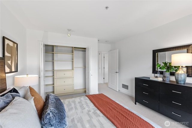 bedroom featuring baseboards, light carpet, a closet, and visible vents