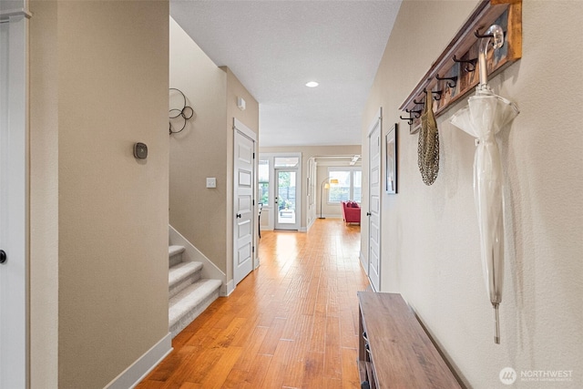 corridor with recessed lighting, baseboards, stairway, and light wood-style floors