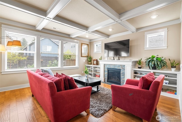living area featuring a fireplace with flush hearth, baseboards, beam ceiling, and wood finished floors
